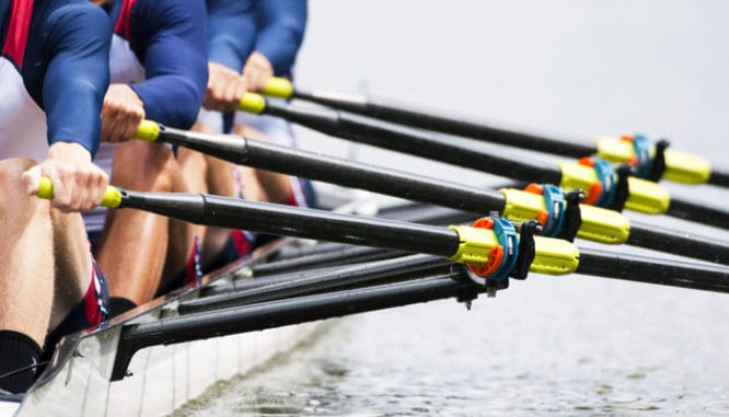 A close up of a team of rowers' oars showing how to invest 5000 dollars in real estate: partner up