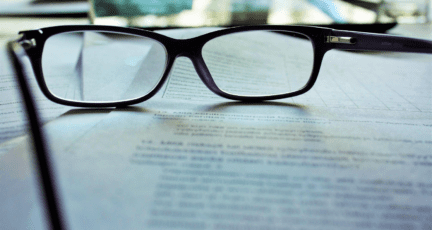 A pair of glasses rest on a contract.