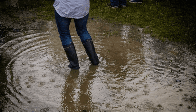 A photo shows a person walking through shallow flooding.