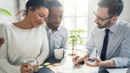 A couple consults with a bearded white mortgage broker