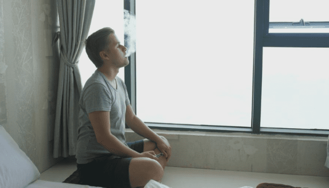 A smoker smoking a cigarette in a house.