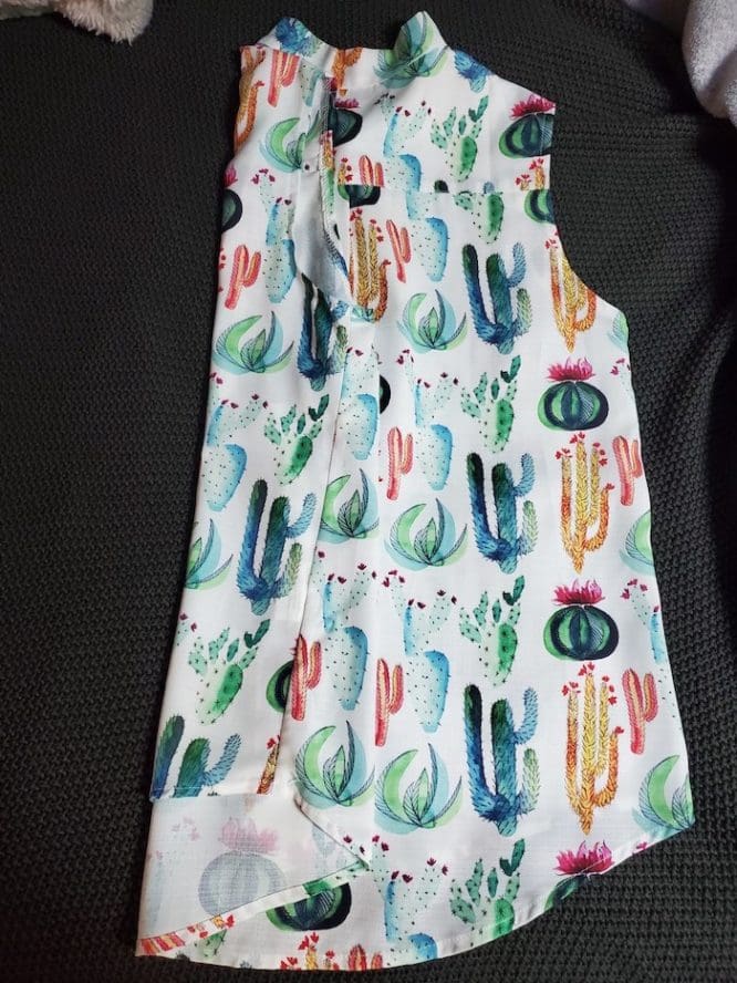 A shirt with a cactus print getting folded into thirds from sleeve to sleeve for a flat-fold step to show how to pack clothes for moving