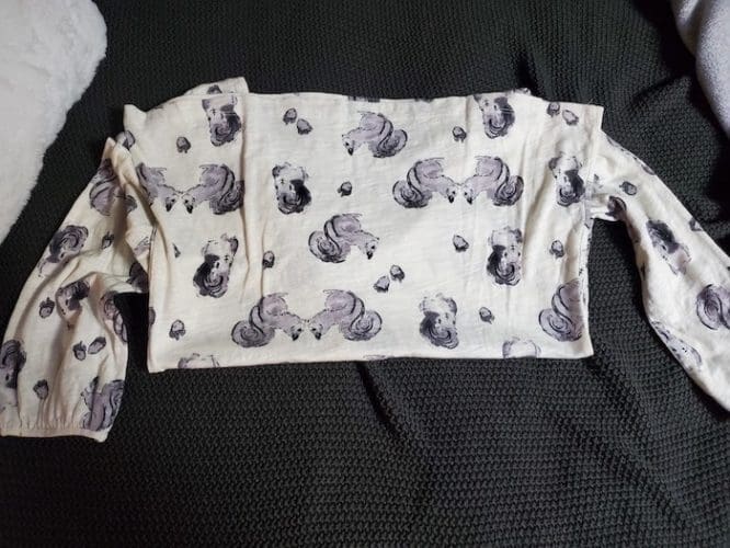 A shirt with a squirrel print laid flat with its bottom hem folded up to its collar and shoulders in the Kon-Mari method step to show how to pack clothes for moving day