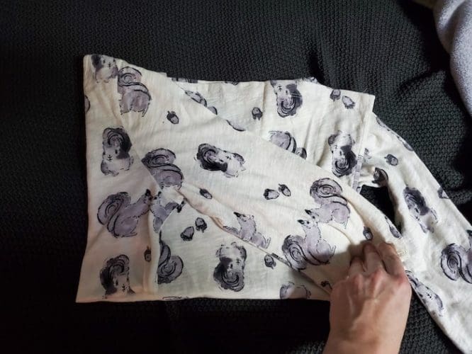 A shirt with a squirrel print with the first (left) side folded over in the Kon-Mari method step to show how to pack clothes for moving day