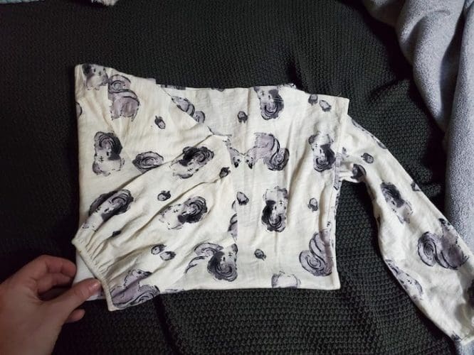 A shirt with a squirrel print with its sleeve folded over in the Kon-Mari method step to show how to pack clothes for moving day