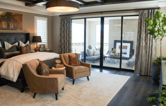 A master bedroom with a balcony and furnished porch through a sliding glass door.