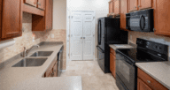 A kitchen with wooden cabinets and black appliances, which could be in a rent to own home.