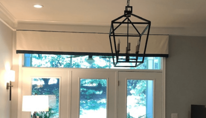 A window valence near a chandelier that is in style.