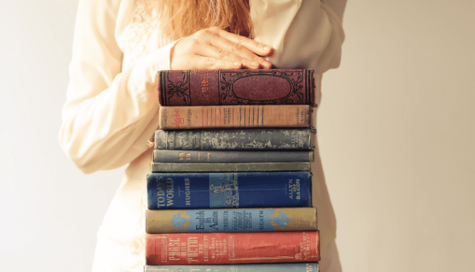 A woman with books that explain the cost to sell a house.