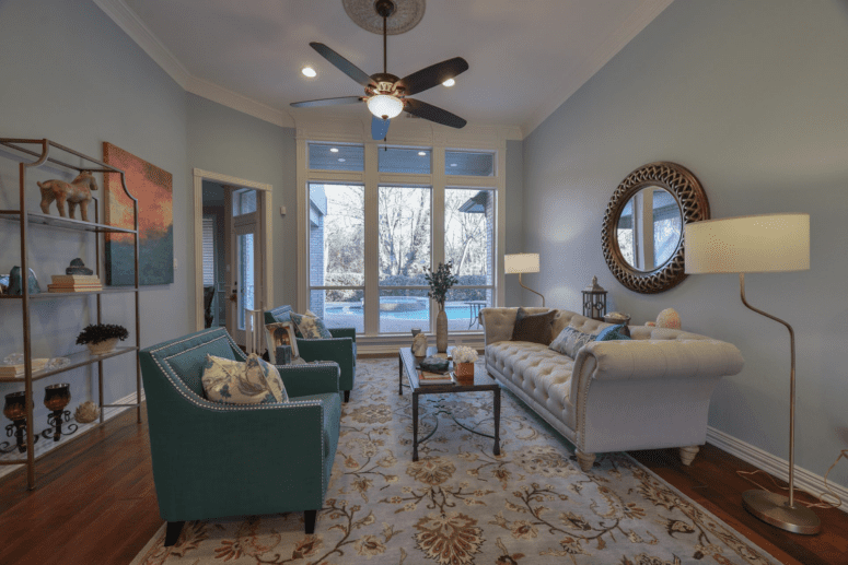 A ceiling fan in a sunny living room that is not out of style.