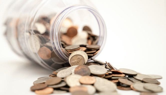 A spilled jar of coins represents the financing part of buying land