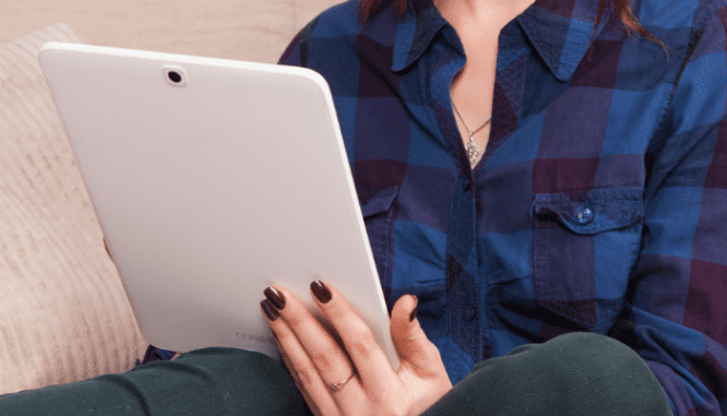 A woman researching how to avoid being house poor on a tablet.