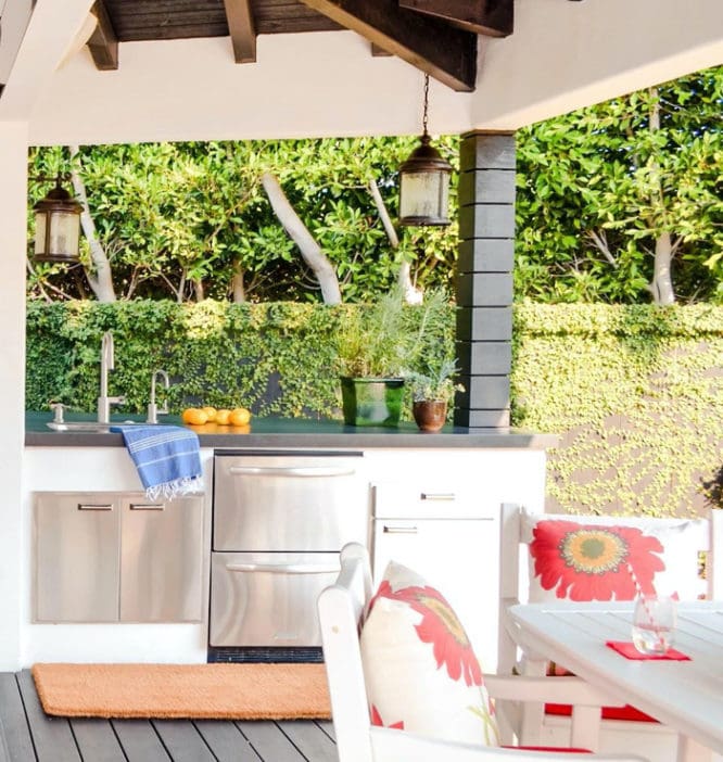 An outdoor kitchen with ovens and a refrigerator.