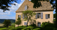 A French country house displaying mute colors and window shutters.