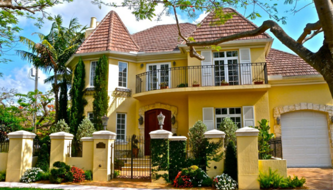 A French country house showcasing window shutters and a Juliet balcony.