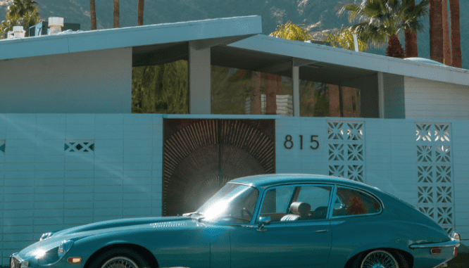 A car parked outside of a midcentury modern house.