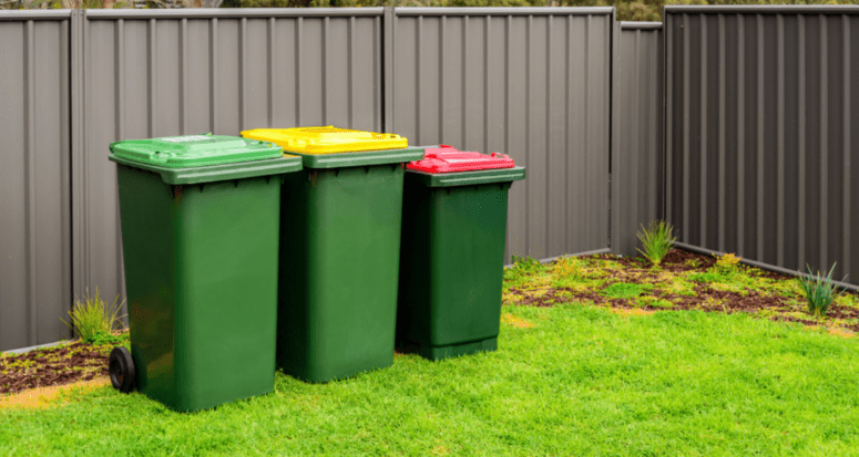 An image of trash cans next to a fence to demonstrate what a trash can fence is.