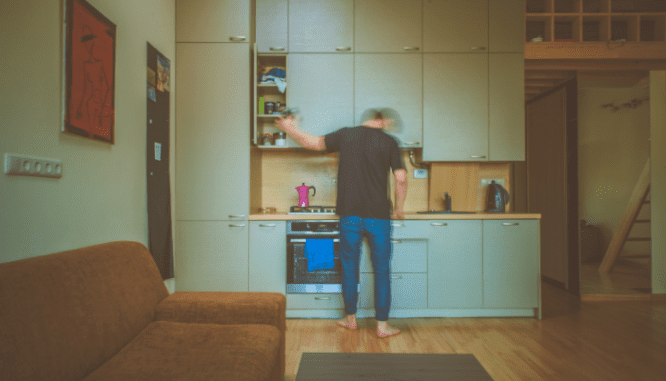 An image of a man using a kitchen to demonstrate what a microapartment is.