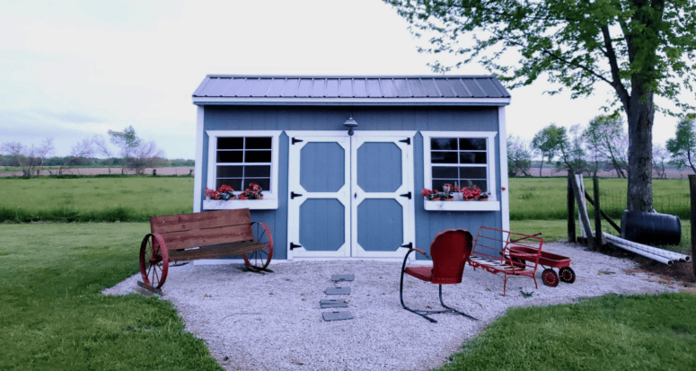 A garden shed spruced up with seating and flower boxes can add to the cost to build a shed.