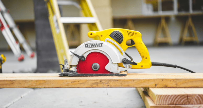 A saw and wooden plank at a home construction site, which can help you decide whether to add on or move.