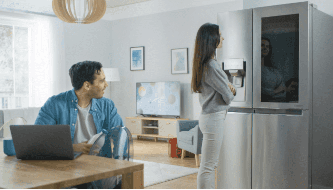 A couple consults the touch screen on their refrigerator in their smart kitchen.