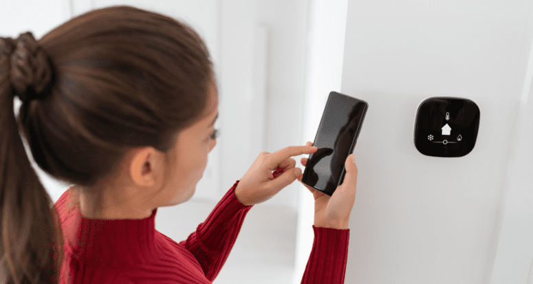 A woman using a smart thermostat.