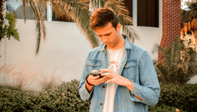 A person using a phone to regulate a smart thermostat.