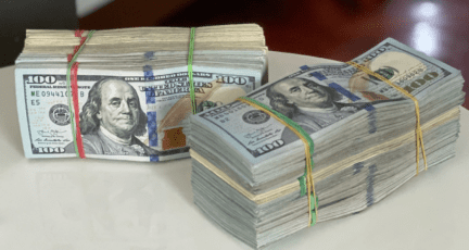 Two stacks of one hundred dollar bills sit on a table after learning what happens when you sell a house for a profit.