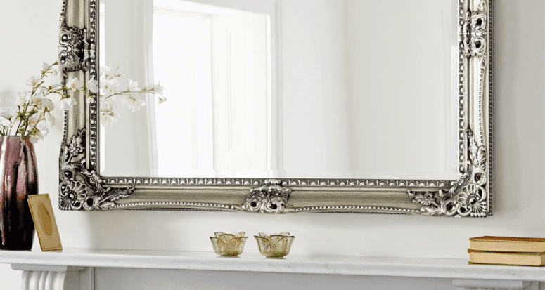 A decorative mirror rests above a fireplace mantel, which is a popular way to decorate with mirrors.