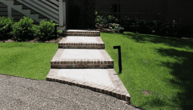 A pathway formed from brick that leads to a house.