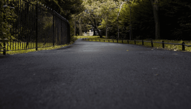 A long asphalt driveway, which can crack and spur homeowners to learn how to fix driveway cracks.