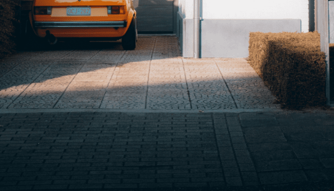 A car is parked on a concrete driveway with stamped designs, which is one way how to fix driveway cracks.