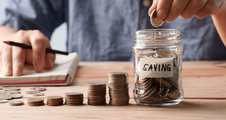 A man puts coins in a jar to symbolize investments to save for a house.