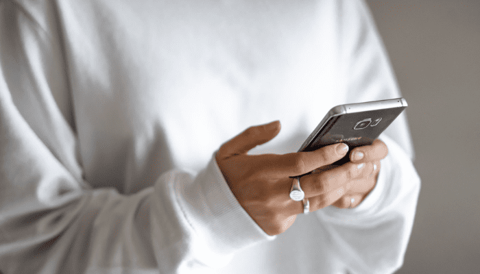 A woman looks at her smartphone and asks herself "why do I keep getting offers on my house?"
