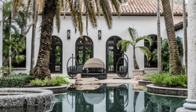 An outdoor room that's surrounding a tropical pool.