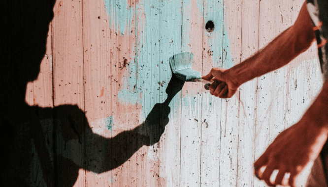 A person painting an exterior wall, which you may need to do before selling your house.