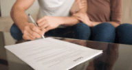 An image of two people signing a loan to demonstrate the cost to refinance.