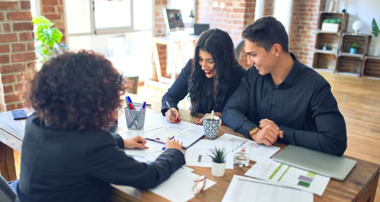 A couple and real estate agent signing mortgage documents.