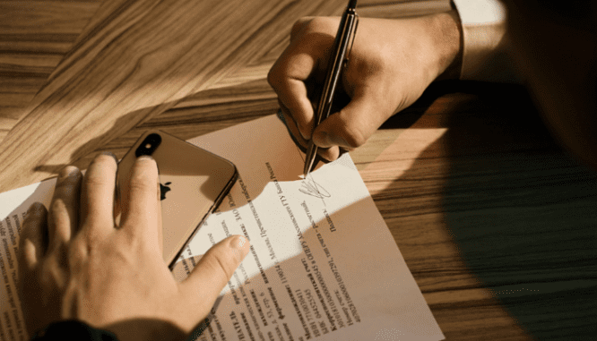 A buyer signing mortgage documents with a pen.