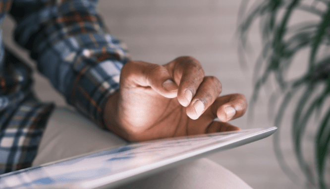 A man using a tablet to determine whether to save for a house or invest.