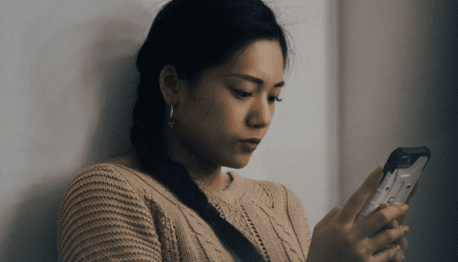 A woman researching on her phone to see if she should refinance her mortgage.