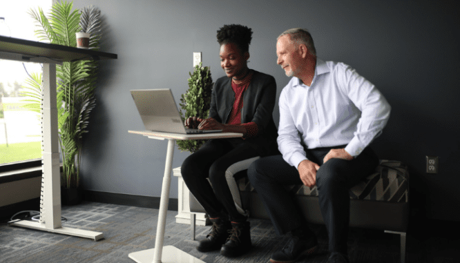 A real estate agent using a laptop to answer a homeowner's question of, "How do I sell my house?"