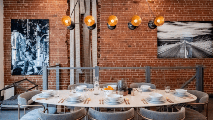 A home featuring sustainable interior design with the reuse of fire hoses found in the basement of an 1896 firehouse as a backlit art installation coming up the stairs.