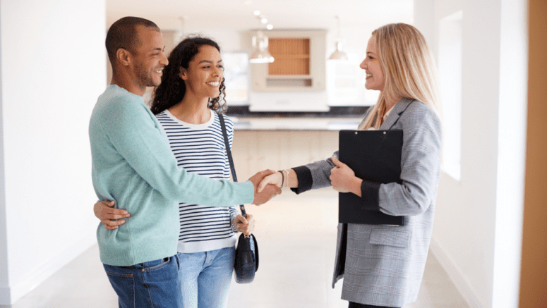 A real estate agent walking a couple around a home for sale.