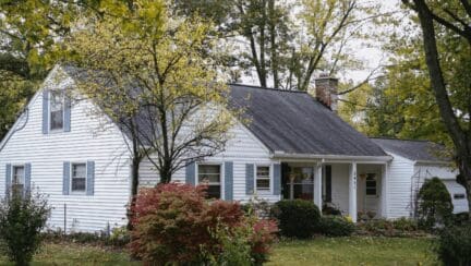 A white house with trees to depict how to sell a fixer upper house fast.