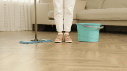 A person with a mop about to deep clean laminate floors.