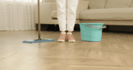 A person with a mop about to deep clean laminate floors.