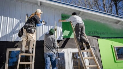 Contractors install the siding on a new house, one of the many steps to building a house.