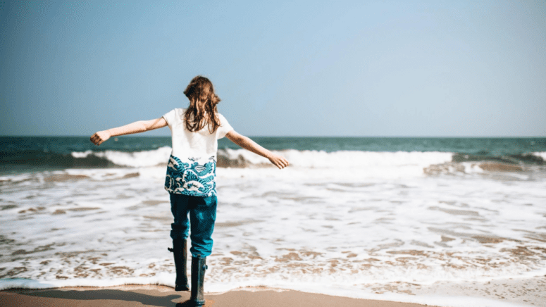 Woman standing standing near the ocean on the coast.