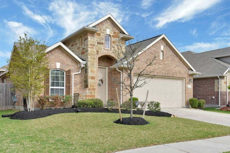 Newly-built stone exterior single-family home with a grassy front yard and an attached garage.